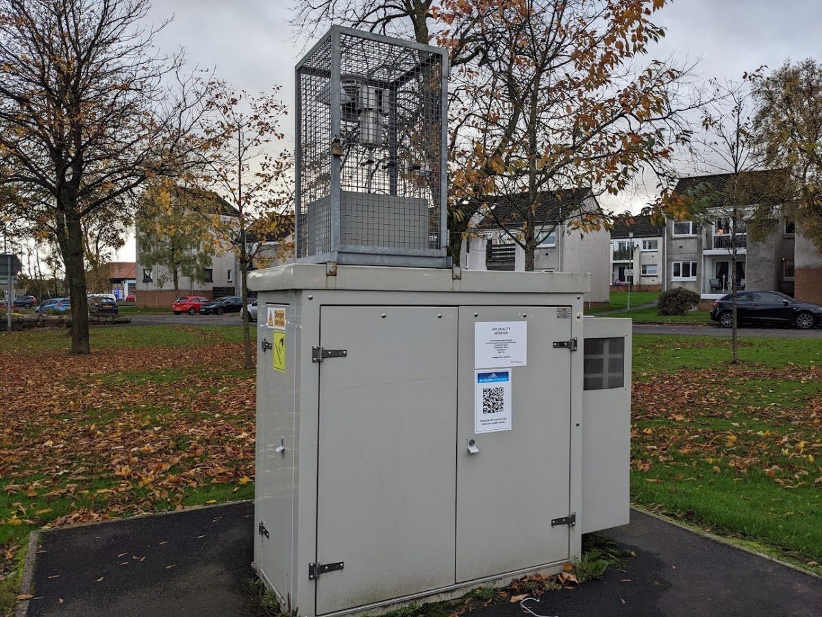 An air quality sensor standing in the park in a residential area 
