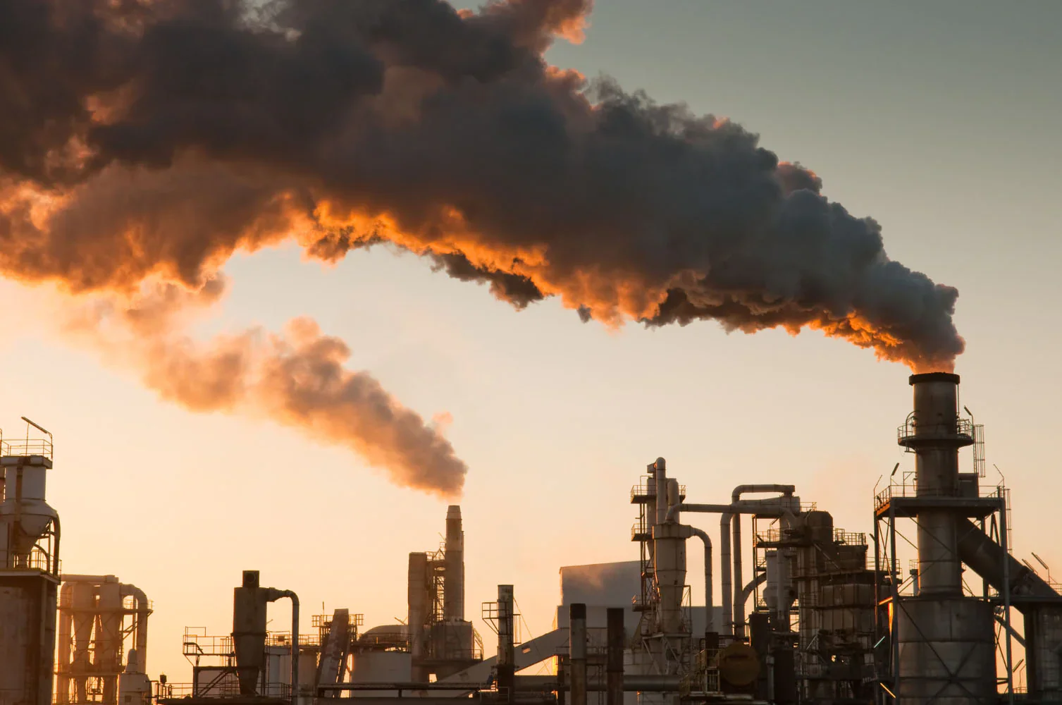 Industrial facility with smokestacks releasing dark smoke