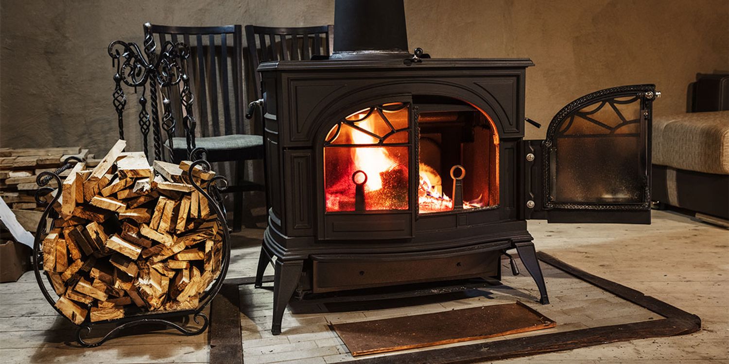 A black wood-burning stove with a glass front, filled with a bright, warm fire. 